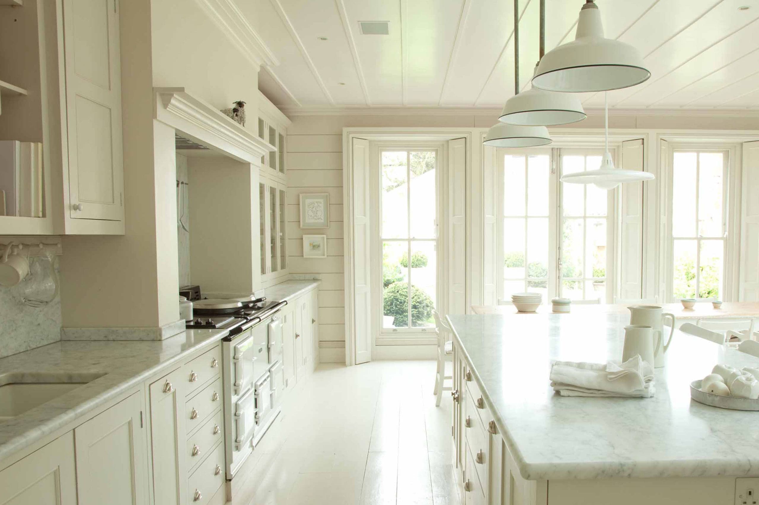  White country kitchen with long dinng table and glass wall cabinets
